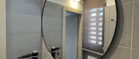 A modern bathroom with a round mirror, a sink, and a towel rack.