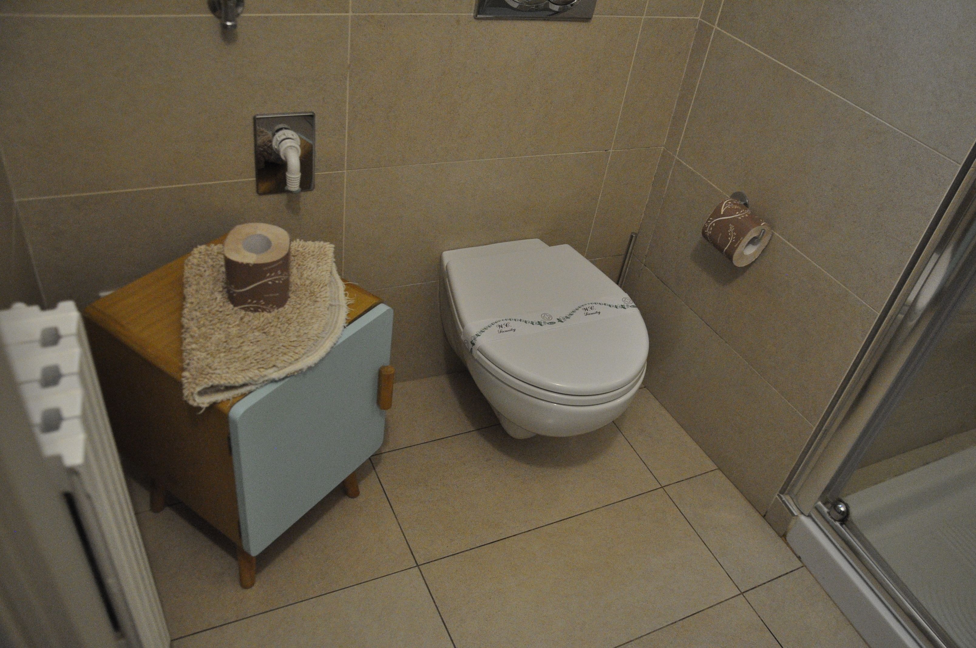 A small bathroom with a toilet, a sink with a towel, and a shower area.