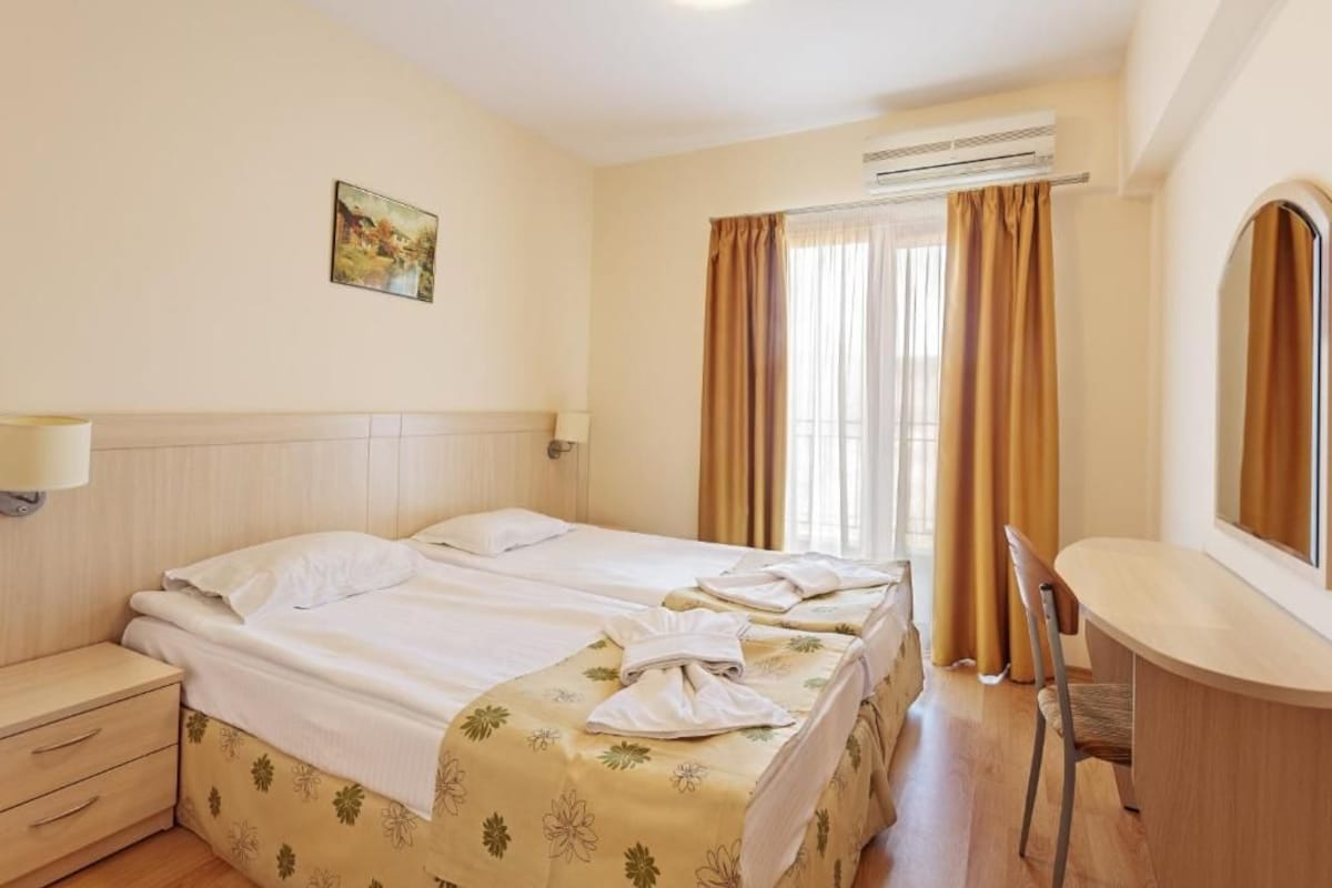 A hotel room with two beds, a desk, and a chair.