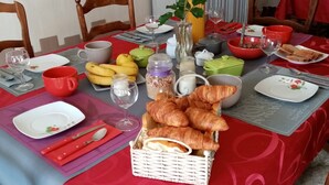 A dining table set with various food items, including bread and fruits, and a vase with flowers.