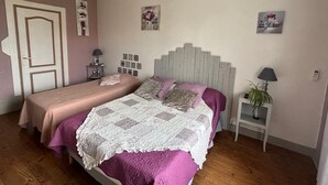 A bedroom with a bed, bedside tables, an air conditioner, and a chandelier.