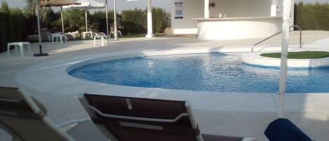 A swimming pool with lounge chairs and umbrellas.