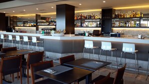 A bar area with a counter, shelves of liquor bottles, and seating with tables and chairs.