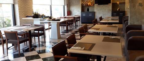 A restaurant with checkered flooring, multiple tables and chairs, a bar area, and a television mounted on the wall.