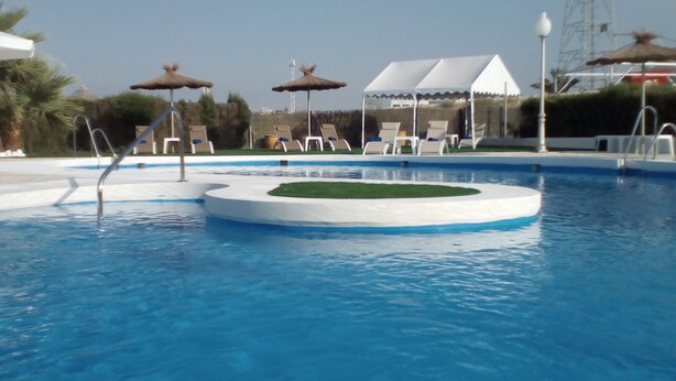 A swimming pool with lounge chairs and umbrellas.