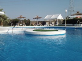 Una piscina al aire libre de temporada, sombrillas, tumbonas
