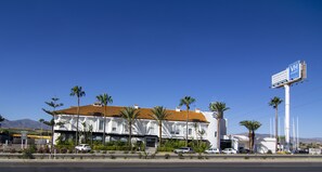 A hotel with a white facade, red-tiled roof, and palm trees in the front. - Avent Verahotel (Vera)