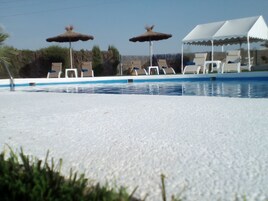 Una piscina al aire libre de temporada, sombrillas