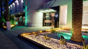 A hotel entrance with a modern design, featuring a glass facade and a well-lit pathway leading to the entrance.