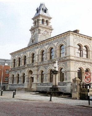 A historic building with a clock tower, arched windows, and a stone facade. - Old Fort Lodge (Sligo)