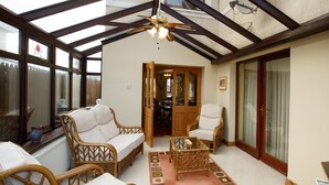 A sunroom with wicker furniture, a ceiling fan, and a view of the backyard.