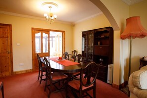 A dining room with a wooden table and chairs, a chandelier, and a cabinet. - Old Fort Lodge (Sligo)