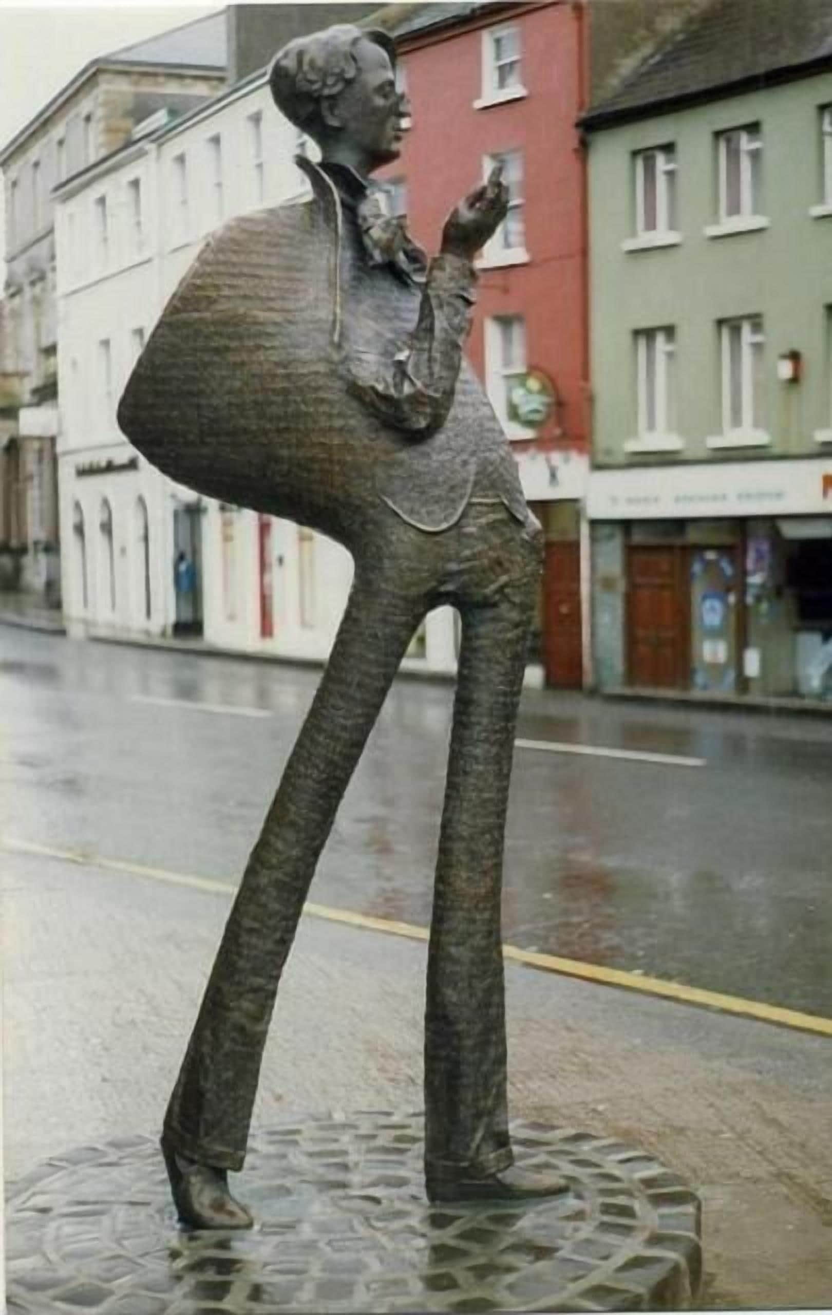 A statue of a person in a suit on a city street.