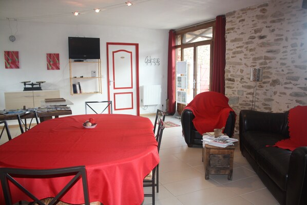 A dining area with a red table, chairs, and a television on the wall.