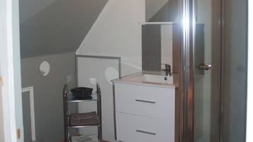 A bathroom with a glass shower enclosure, a white sink, and a towel rack.
