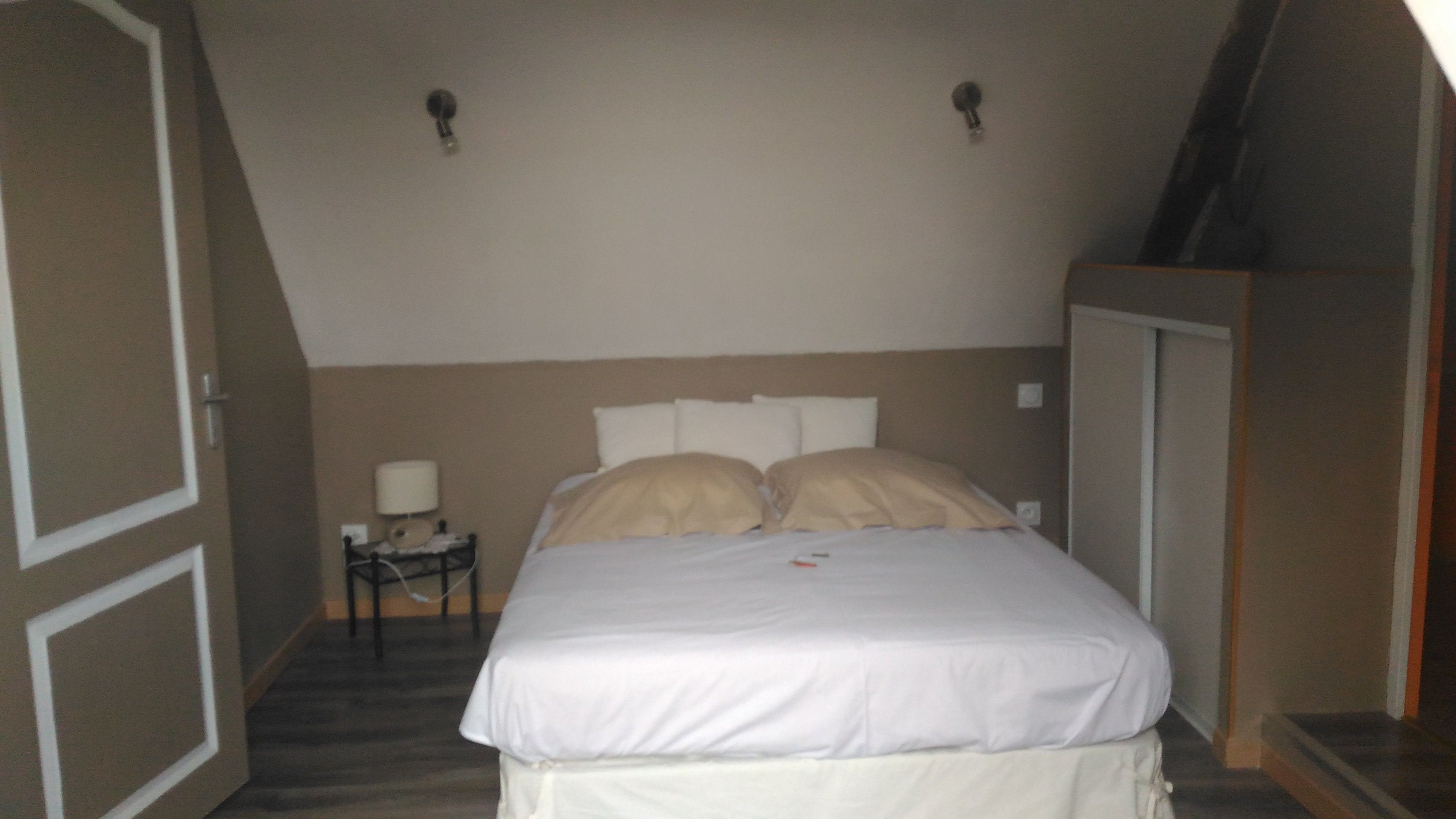 Um quarto com cama, mesa de cabeceira e guarda-roupa.