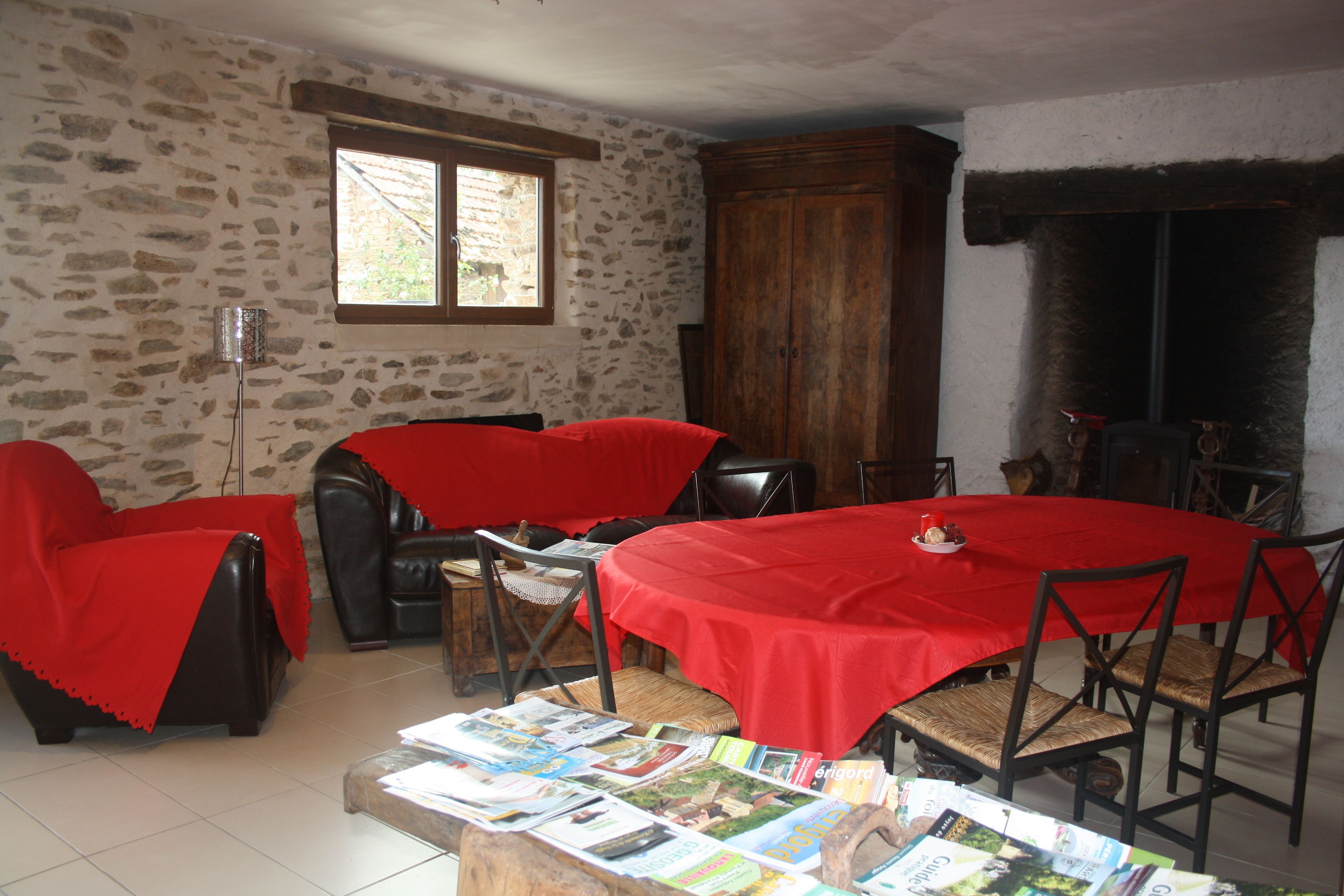 A dining area with a red tablecloth, stone walls, and a fireplace.