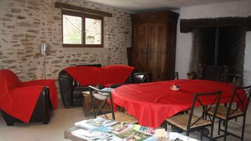 Uma sala de jantar com toalha de mesa vermelha, paredes de pedra e lareira.
