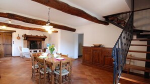 A spacious dining area with a wooden table and chairs, a fireplace, and a staircase with a metal railing. - Agriturismo Il Corniolo (Castiglione di Garfagnana)