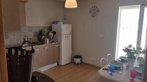 Una cocina compacta con refrigerador, un lavamanos y un comedor con una mesa dispuesta para dos.