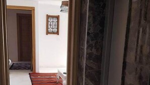A hallway with a marble wall, a doormat, and a door. - Maryouma Appart (Nabeul)