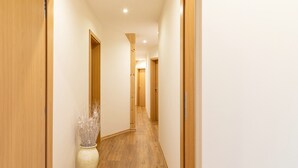 Un pasillo con suelo de madera y puertas, que conduce a otra habitación.