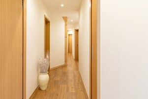 Un pasillo con suelo de madera y puertas, que conduce a otra habitación.