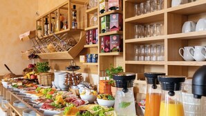 Un bufé con diversos alimentos, incluyendo carnes, quesos y frutas. También hay varias botellas de bebidas y una variedad de copas.