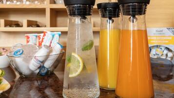 Three glass bottles with different colored liquids, a bowl of ice, and some packets on a countertop.