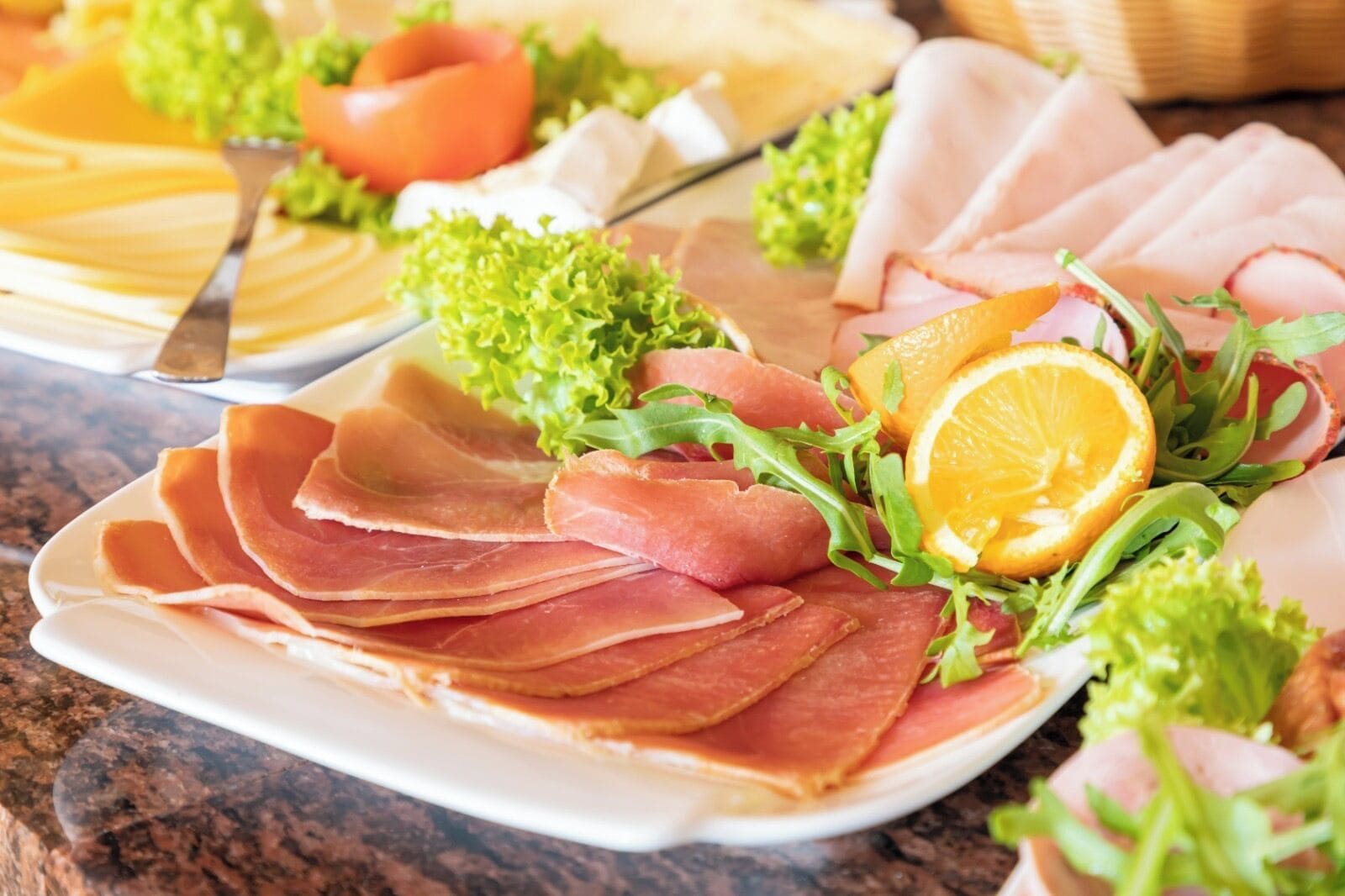 A plate of sliced cured meat garnished with lettuce and an orange slice.