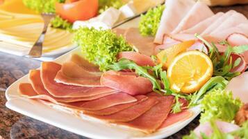 A plate of sliced cured meat garnished with lettuce and an orange slice.