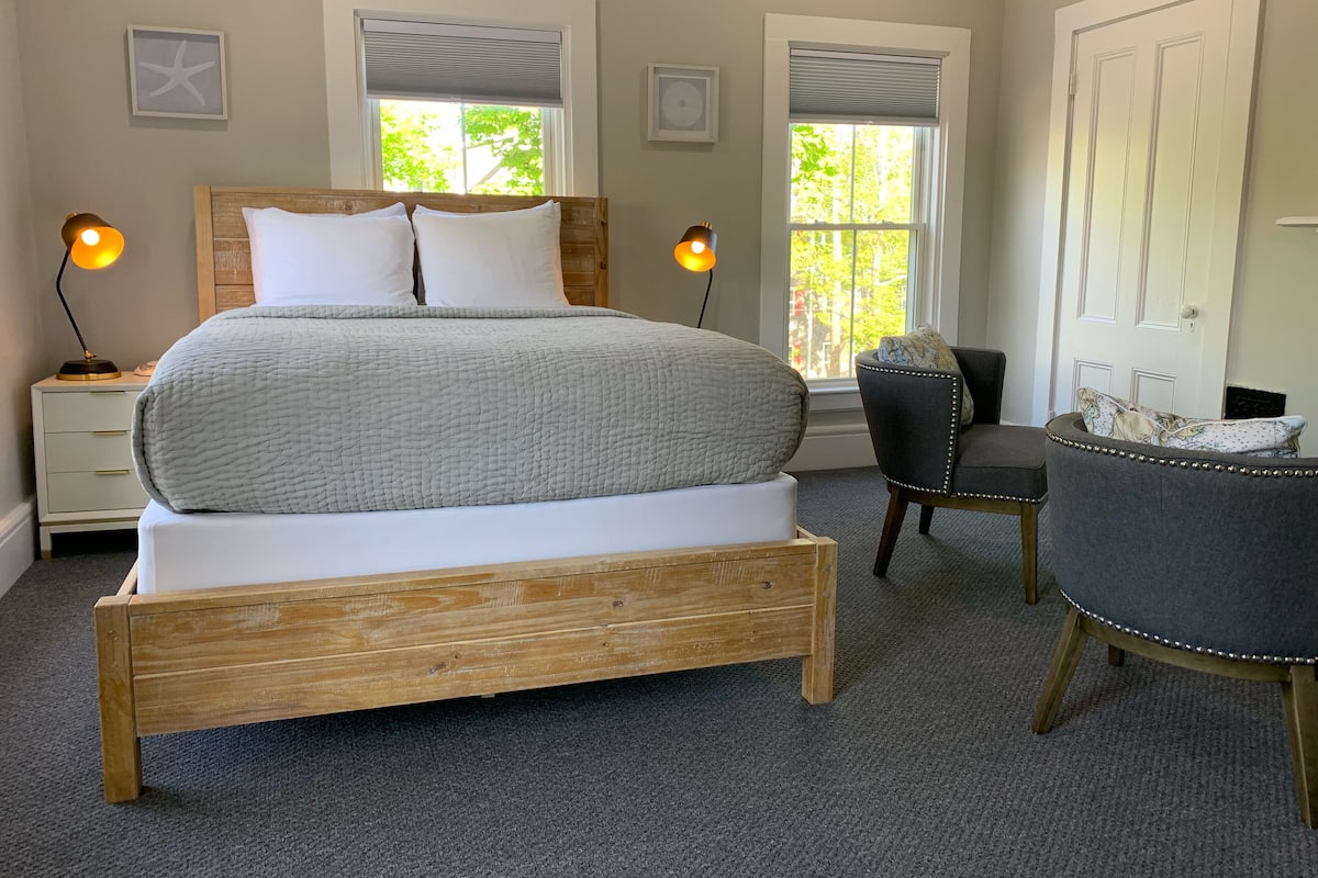 Une chambre à coucher avec un lit en bois, deux lampes de chevet, une chaise et un bureau.