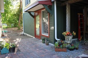 Une maison avec un chemin en briques menant à la porte d’entrée, entourée de plantes en pot et d’un petit jardin.
