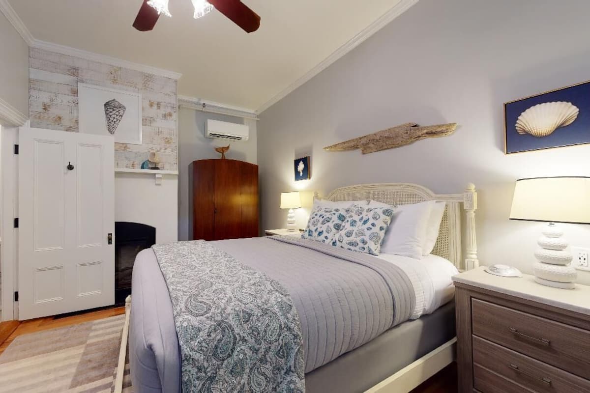 Une chambre à coucher comprenant un lit, des tables de chevet, une armoire et un ventilateur de plafond.