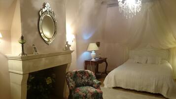 Une chambre à coucher avec un lit, une chaise, un miroir, une cheminée et un lustre.