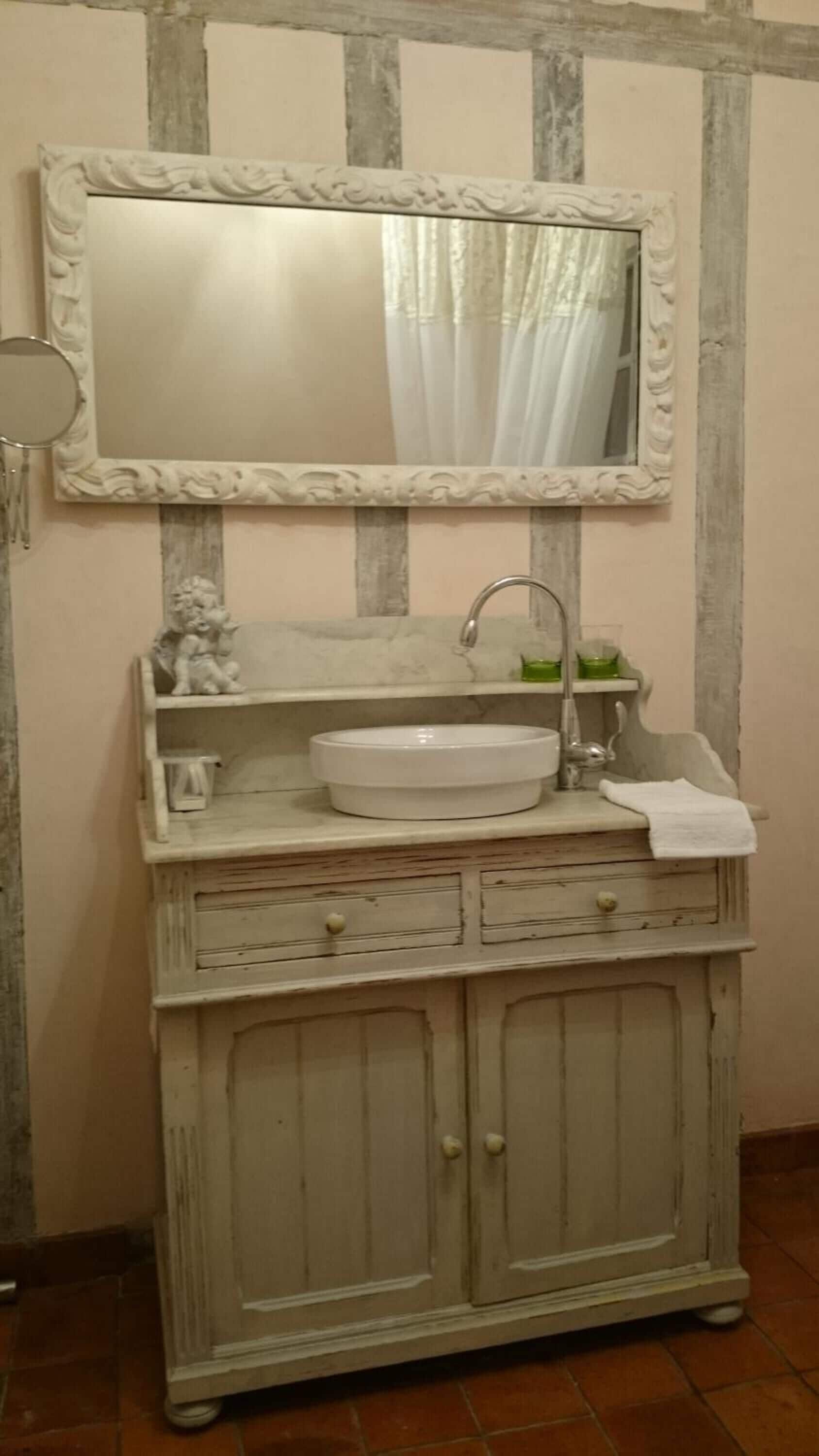 A vintage-style vanity with a large mirror, a sink, and a cabinet below.