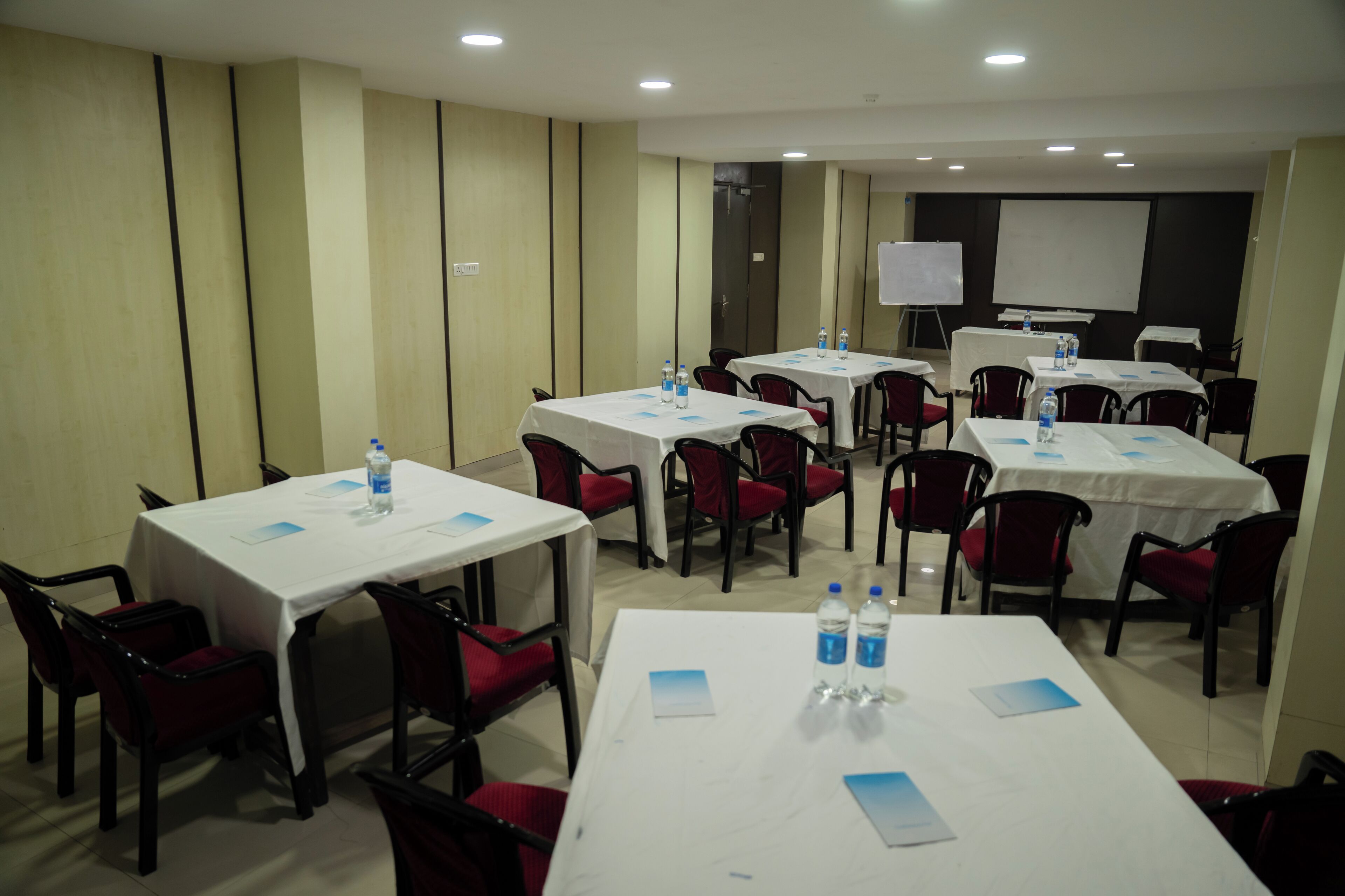 Une salle de conférence dotée de plusieurs tables et chaises, ainsi que de bouteilles d’eau et de documents.