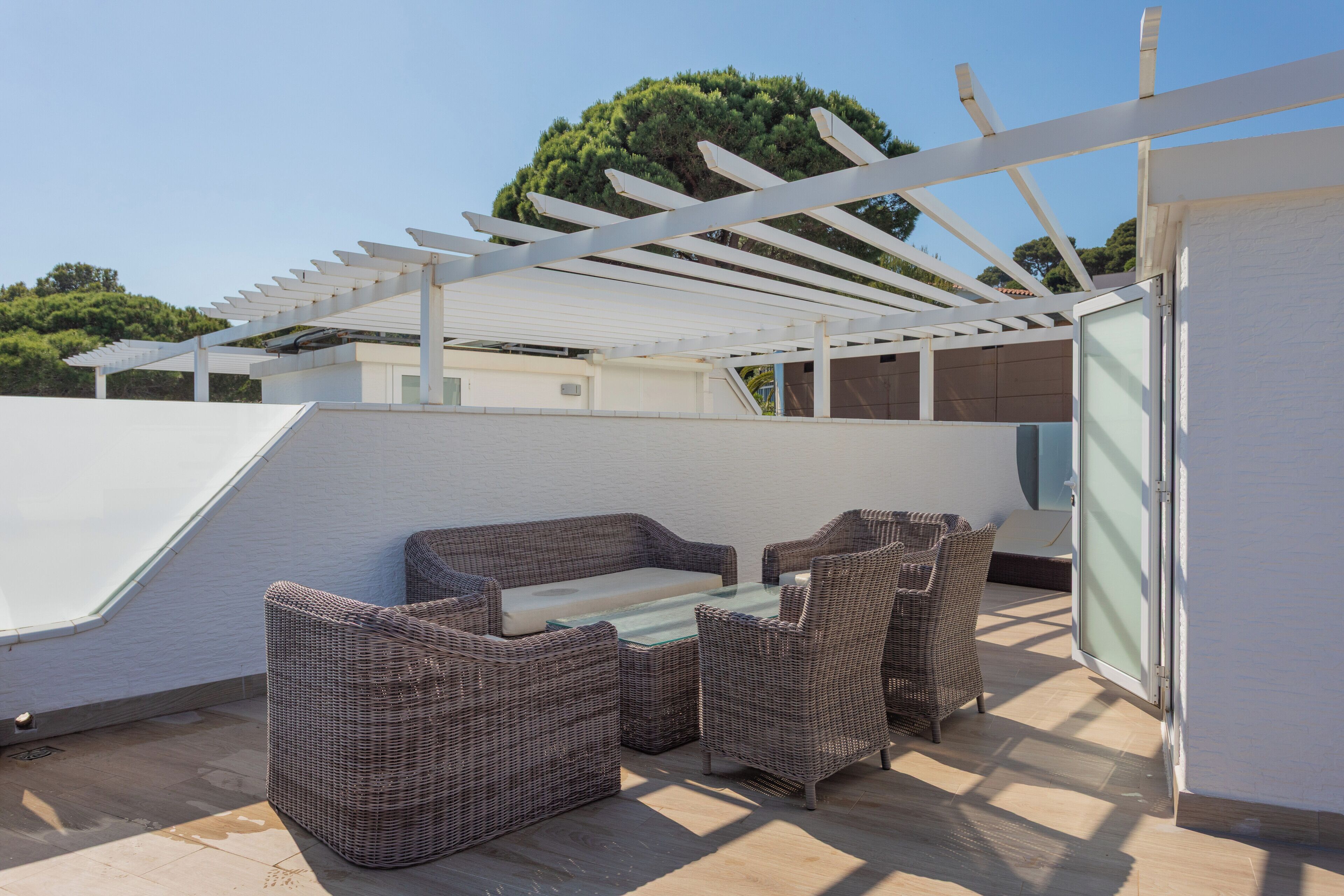 A covered outdoor seating area with wicker furniture and a pergola structure.