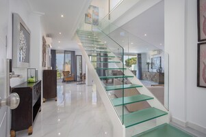 Un interior moderno con una escalera de cristal, un comedor y una sala de estar.