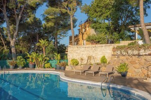 Una piscina con sillas de descanso y plantas en macetas.