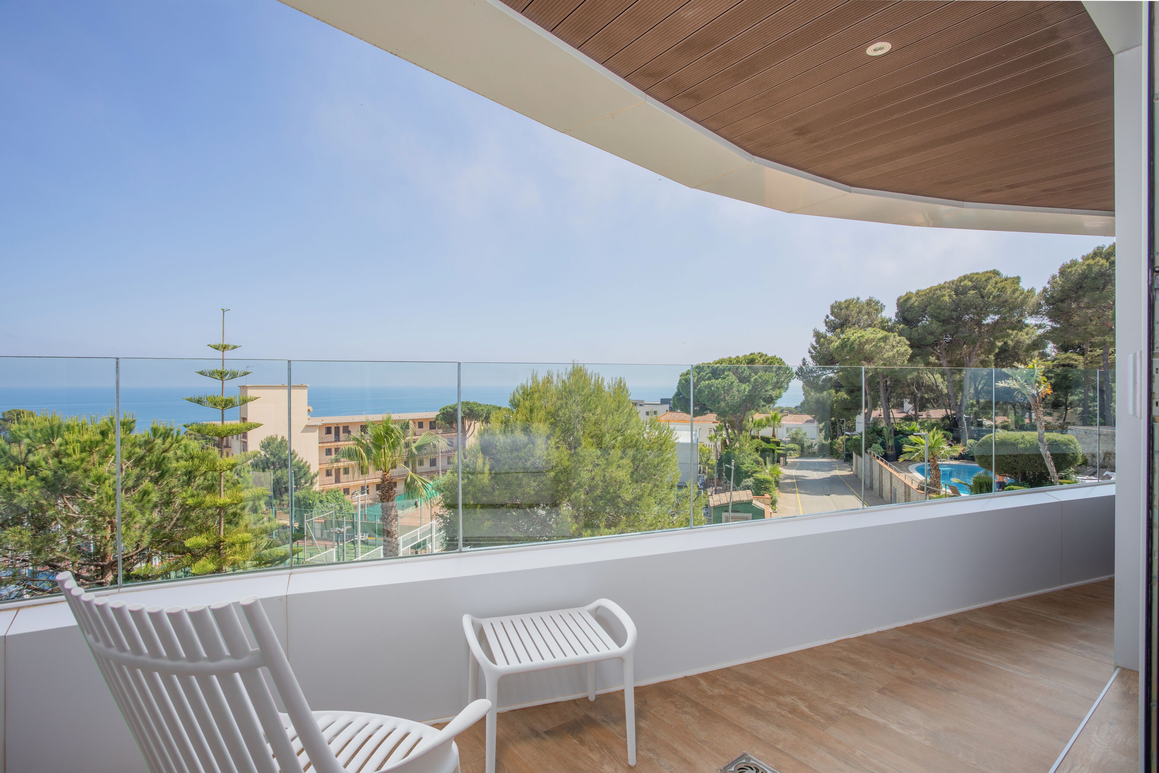 A balcony with a view of a pool, trees, and buildings.