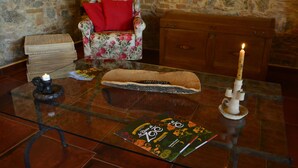 Een glazen tafel met een afstandsbediening, een kaars, een boek en een rieten mand.