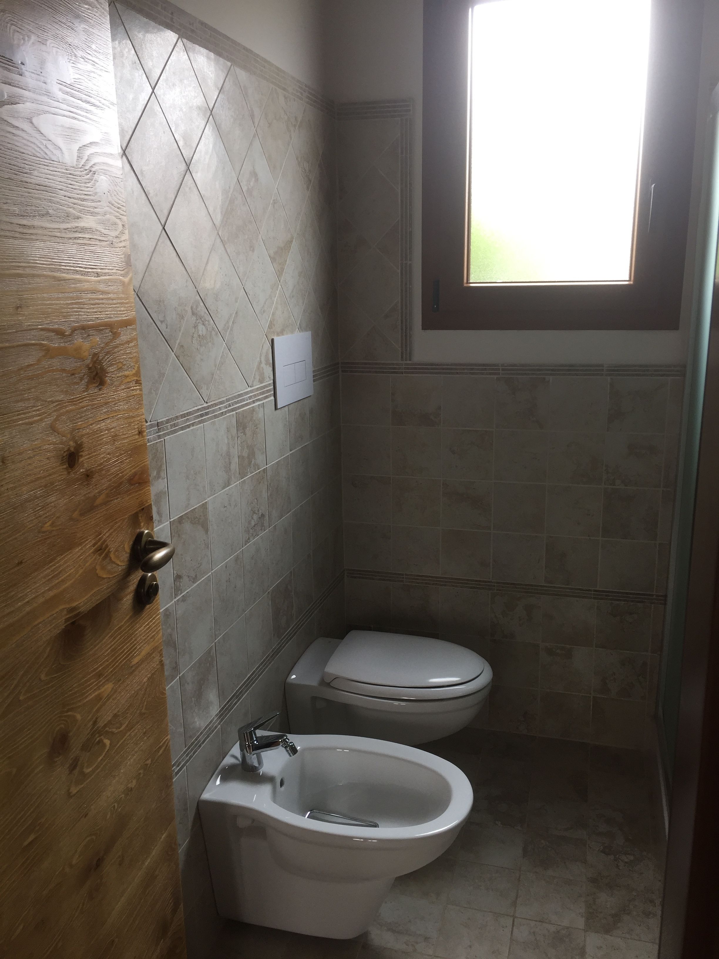 Une petite salle de bain avec des toilettes, un bidet et une porte en bois.