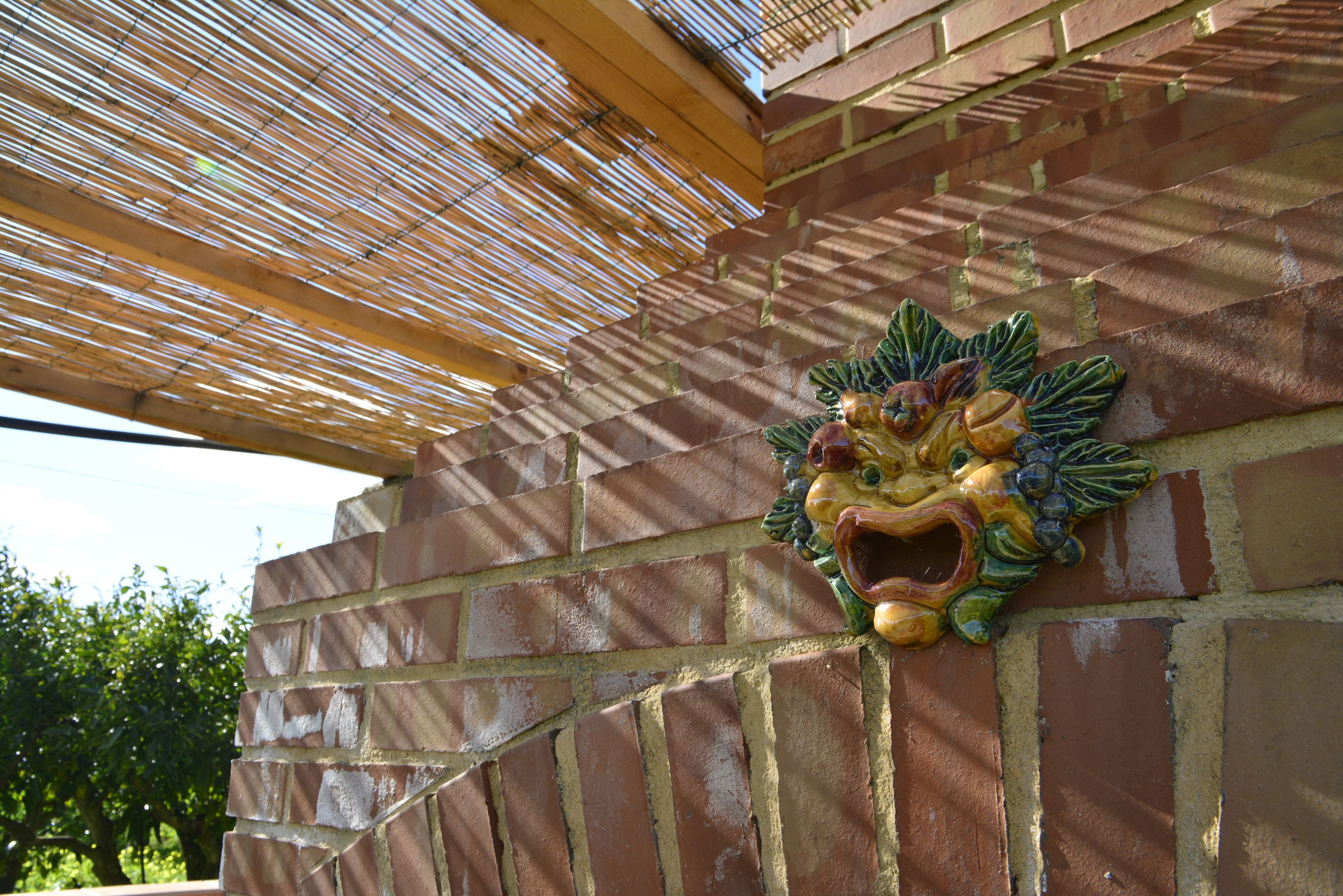 Un mur de briques orné d’une sculpture représentant la tête d’un lion.
