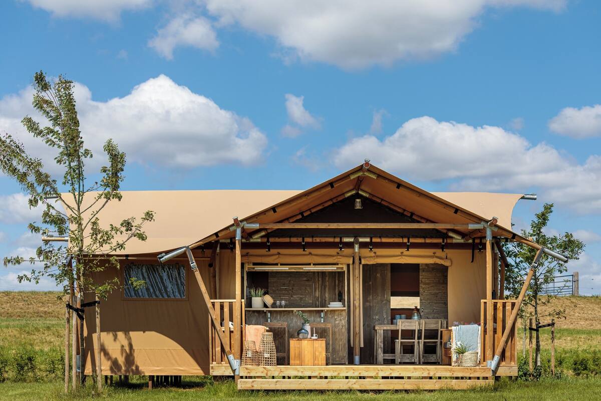 Eine Holzhütte mit überdachter Veranda, einem kleinen Tisch und einem Stuhl.