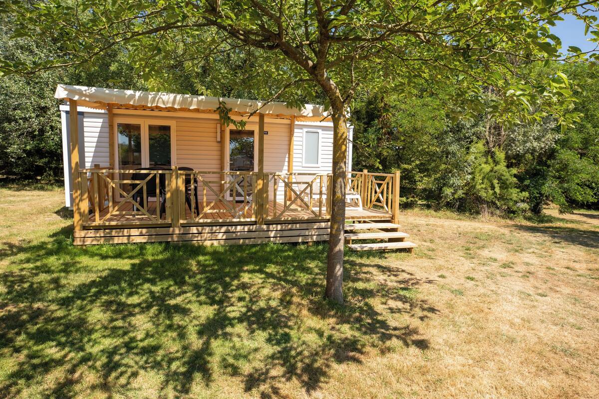 Eine kleine, eingeschossige Holzhütte mit Veranda und einem umzäunten Deck.