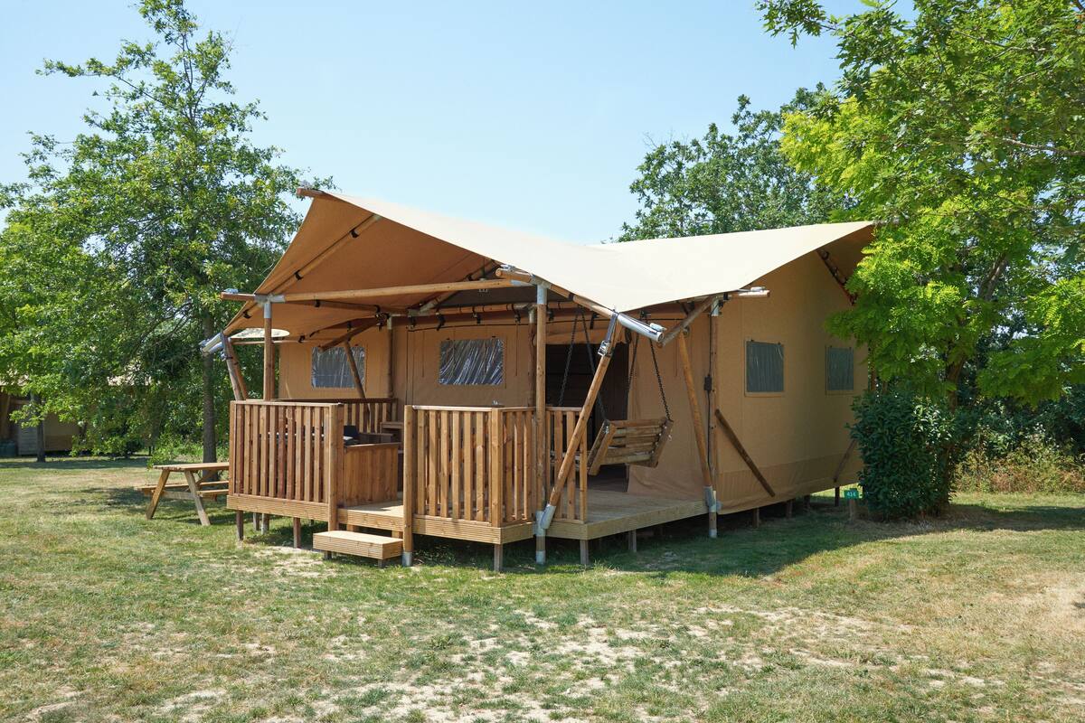 Eine Holzhütte mit einer Terrasse, einer Veranda und einer kleinen Sitzgelegenheit im Freien.