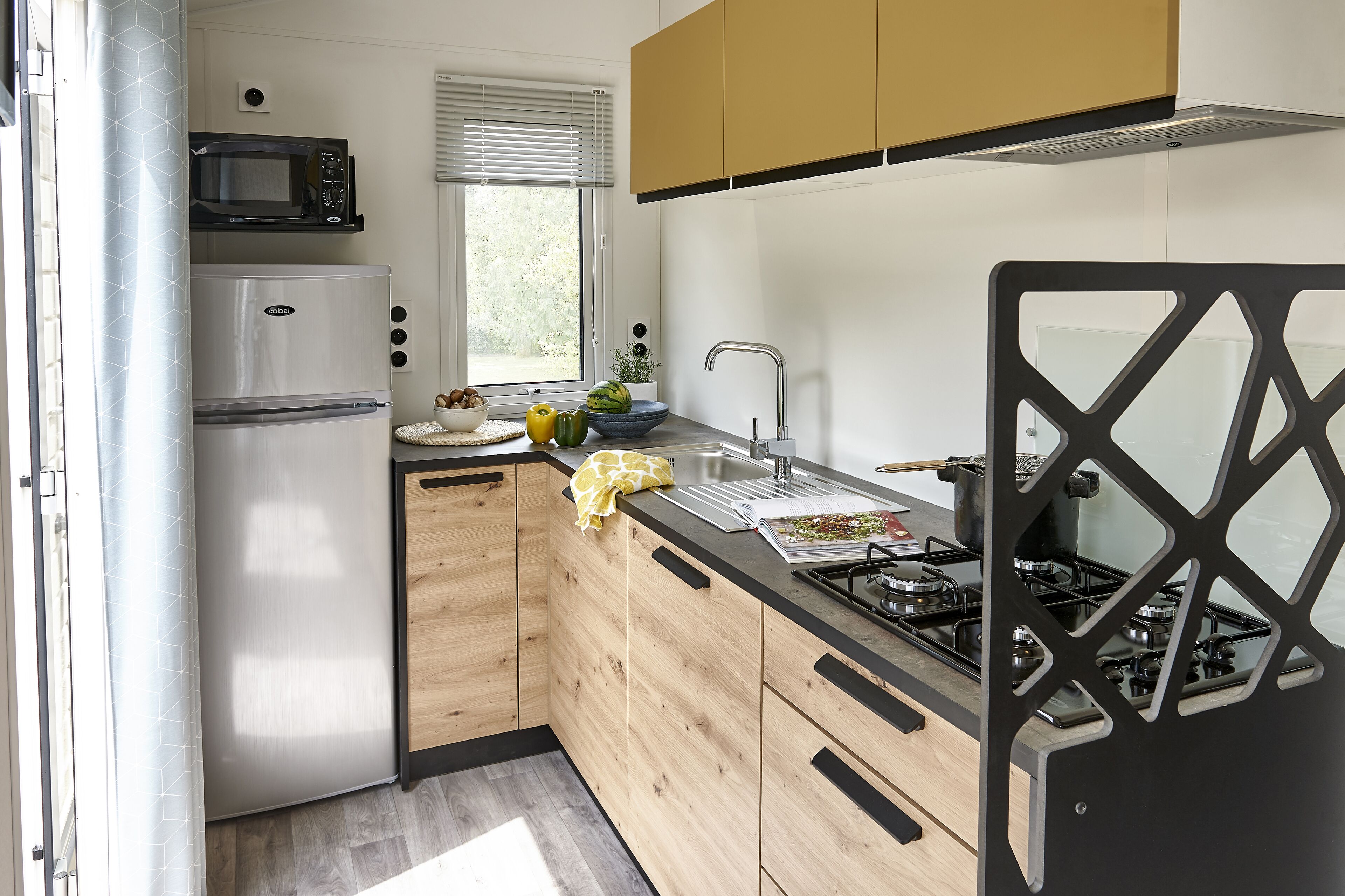 A modern kitchen with a stainless steel refrigerator, a microwave, a sink, and a gas stove.