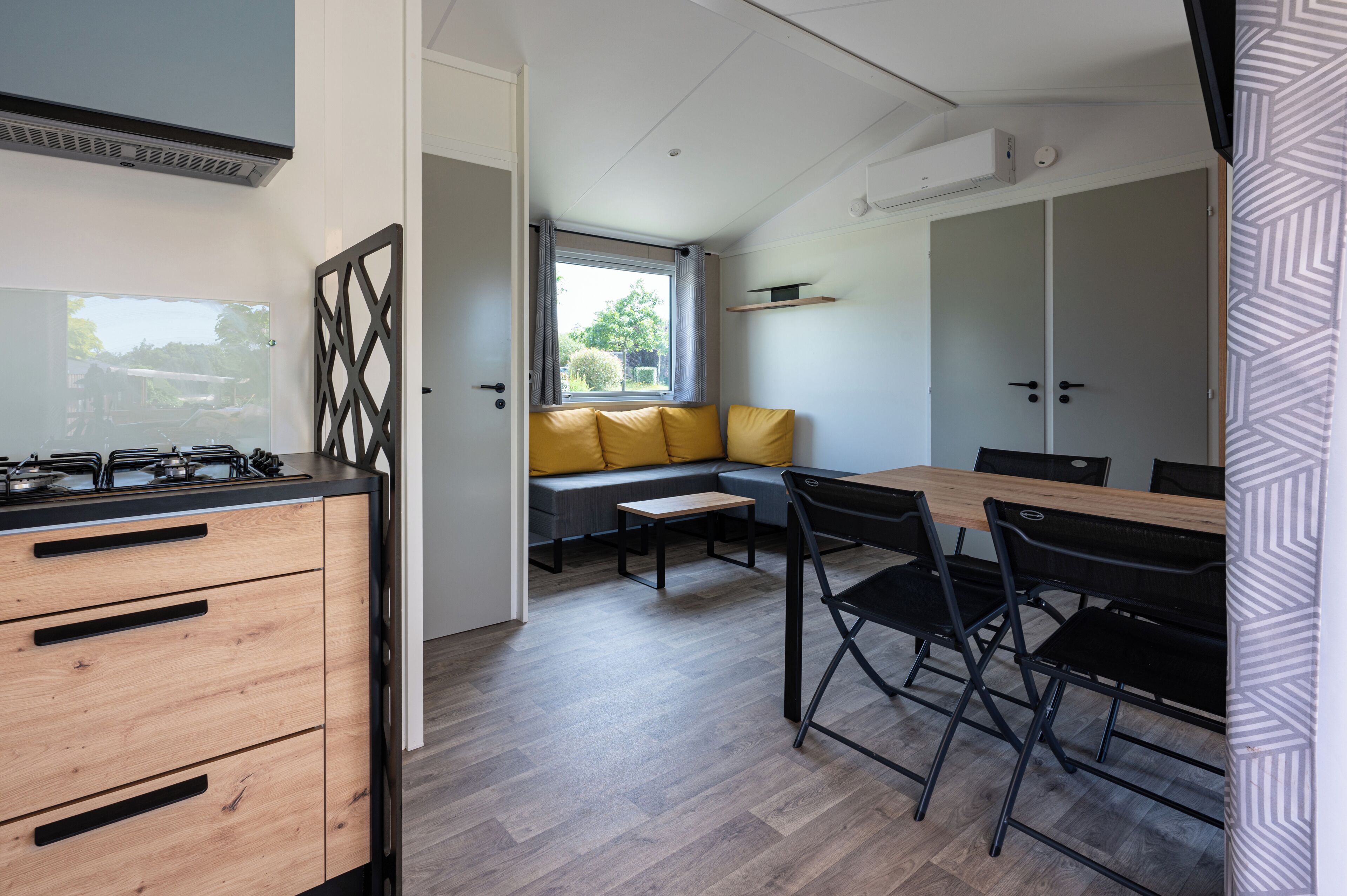 A compact kitchen with a gas stove, wooden cabinets, and a dining area with a table and chairs.