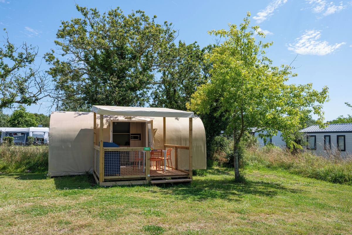 Ein kleines, eingeschossiges Mobilheim mit überdachter Veranda und einem eingezäunten Außenbereich.